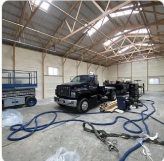 Spray foam rig and hose lines staged for a large shop insulation job